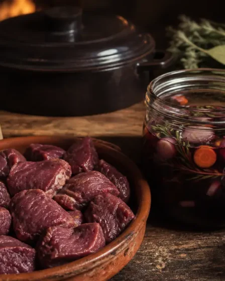 Marinade chevreuil vin rouge en cours : vin rouge, herbes, légumes sur planche bois